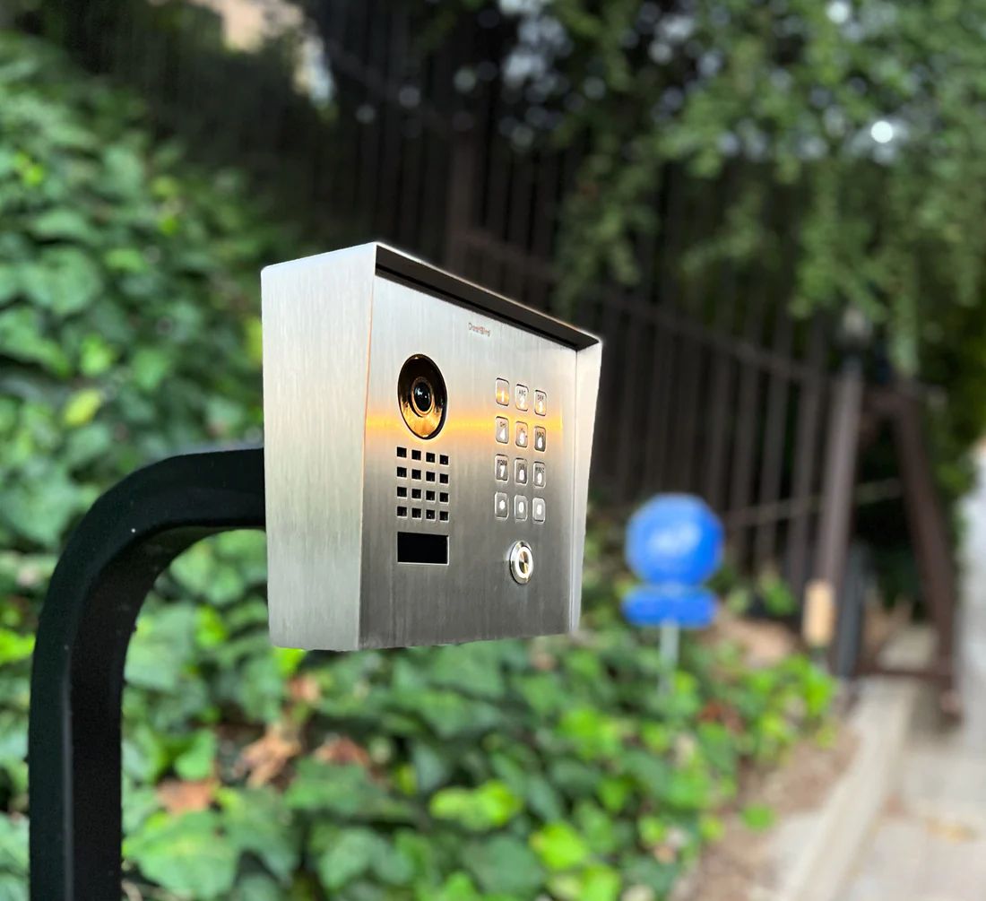 DoorBird video intercom and keypad at a driveway gate entrance